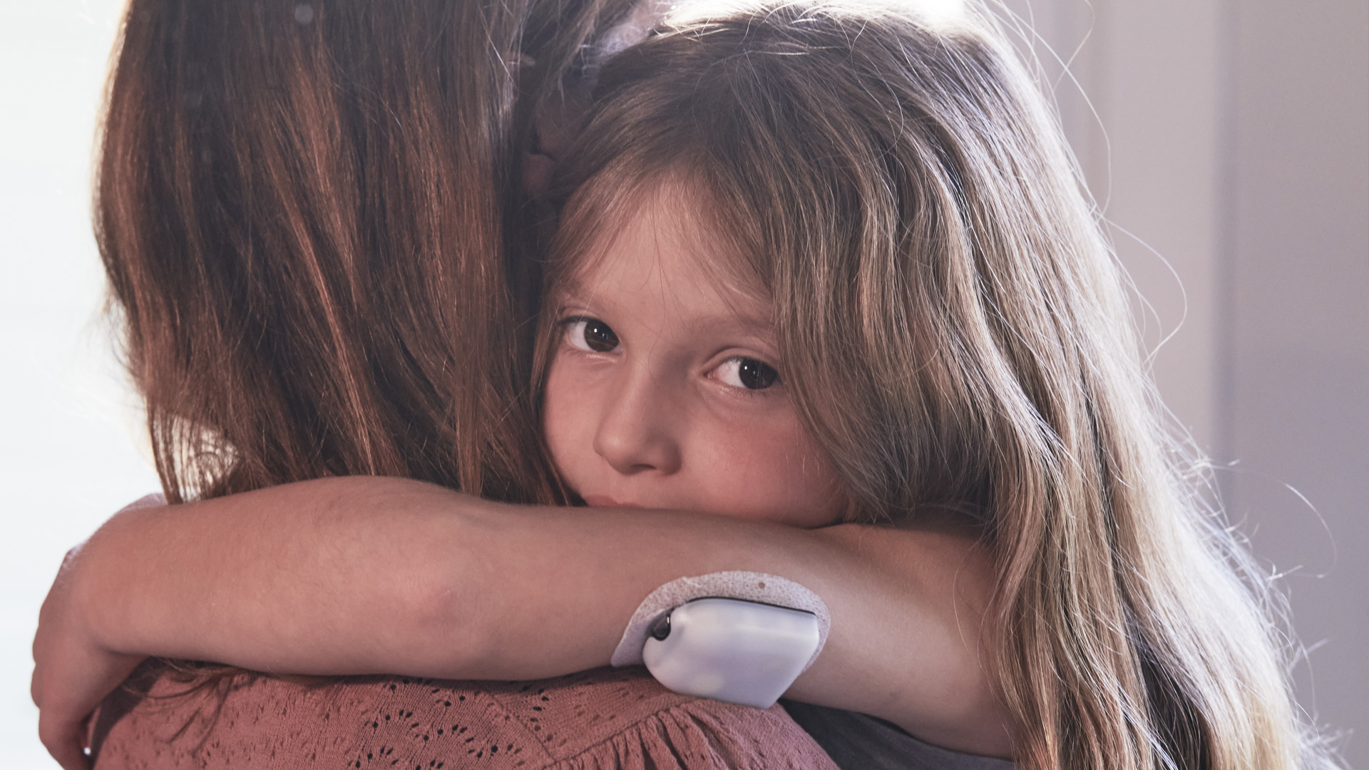 Barn med slanglös insulinpump kramar förälder